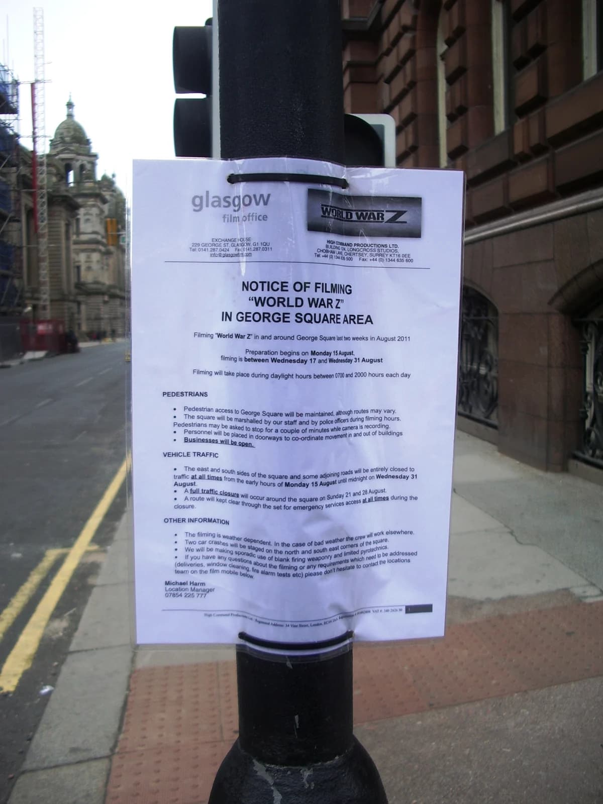 A production notice is attached to a street post near a film location in Glasgow.