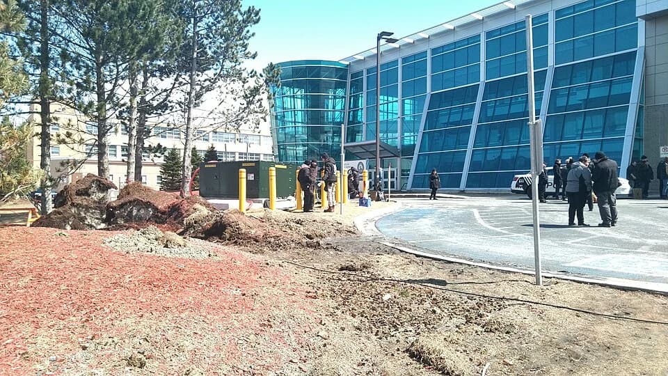 A production crew arranges equipment and positions beside a modern building.
