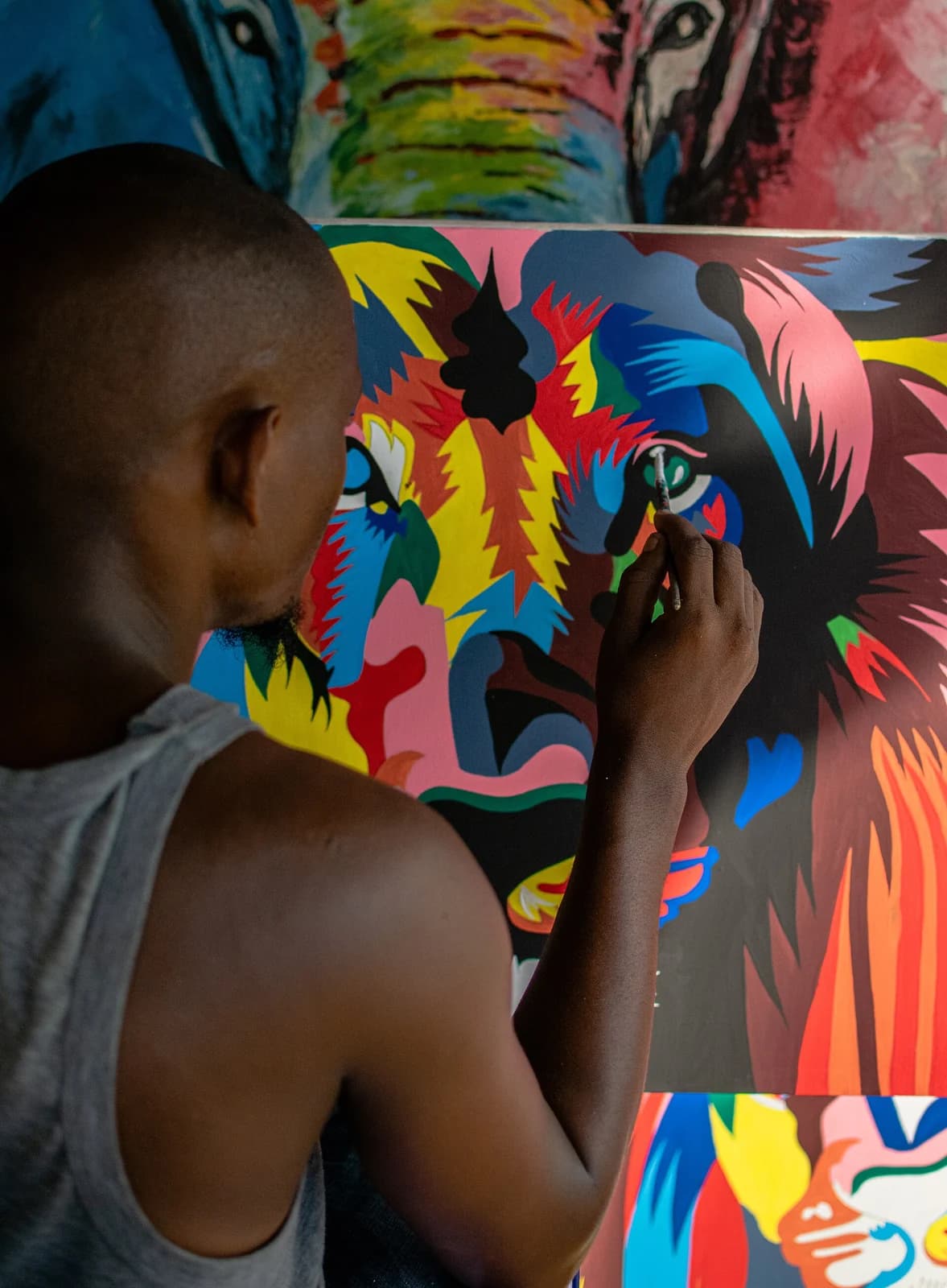 A painter works closely on a brightly colored canvas in Dar es Salaam.