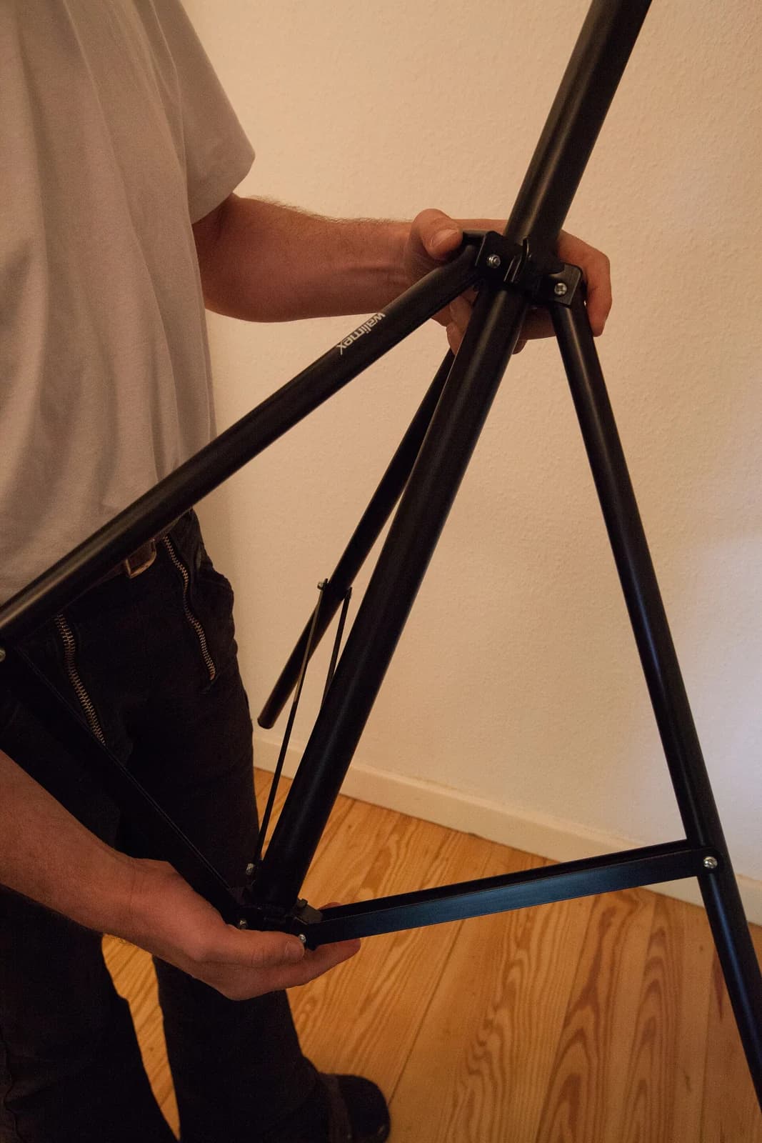 A person adjusts the support stand of studio lighting equipment.